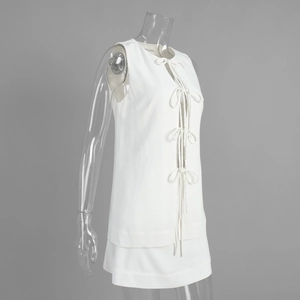 Detail of white sleeveless top with lace-up bow closures and layered mini skirt