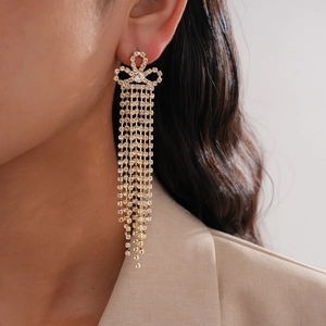 Boucles d'oreilles pendantes à fleurs dorées avec strass brillants portées par modèle