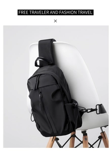 Detail view of black nylon chest bag with multiple zipper compartments on a chair