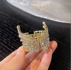 Detailed view of a golden alloy ponytail clip with sparkling rhinestones and crown accents