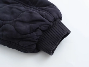 Détail d'une veste matelassée bleu marine avec coutures oignons et poignets côtelés