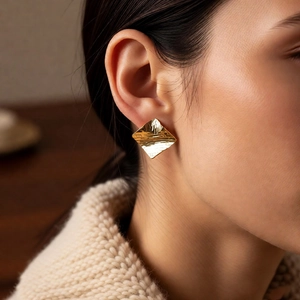 Close-up of 18k gold plated square stud earrings with hammer texture on model wear