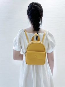 Close-up of a mini yellow PU leather backpack featuring litchi grain texture on model back