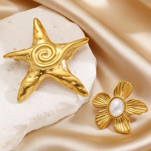 Close-up of golden starfish brooch and pearl flower pin on elegant champagne silk fabric