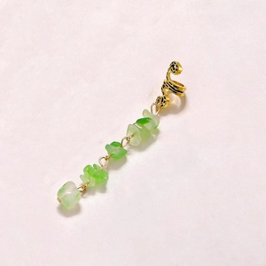 Detailed view of a gold textured ear clip with natural green stone drop pendant on white background