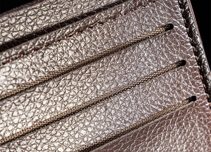 Detailed close-up of dark brown pebble grain leather wallet with precision stitching