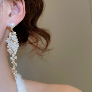 Detailed close-up of elegant gold tassel earrings with pearls and floral petal accents
