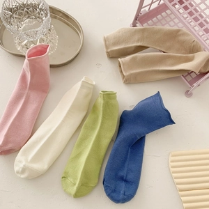 Assorted candy-colored cotton socks in pink, beige, and blue with a stylish rolled edge