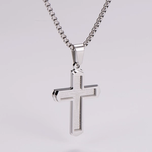 Close-up of stainless steel cross necklace with engraved Spanish Lord's Prayer text