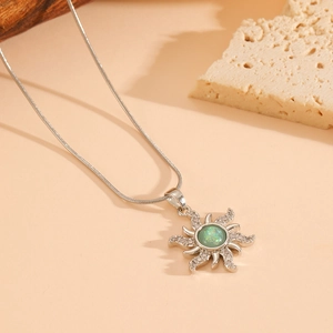 Detail of silver sun necklace with green opal center and sparkling clear crystals