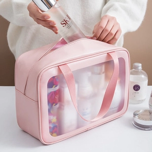 Detail showing hands placing skincare into a large capacity pink PU and PVC travel wash bag