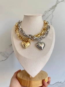 Detail of chunky gold and silver chain necklaces with polished heart pendants on display