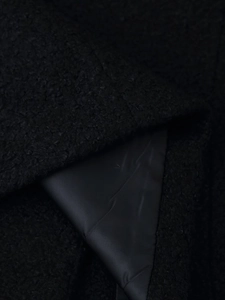 Detail of black teddy fleece texture with smooth satin lining on winter wool coat