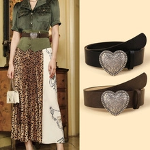 Detail of vintage heart-shaped metal buckle with floral engraving on leather belts