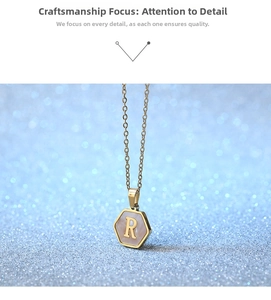 Close-up of hexagonal gold titanium steel necklace with pink shell and letter R pendant