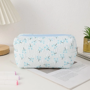 Macro detail of white and blue floral pencil case featuring pleated fabric texture and zipper