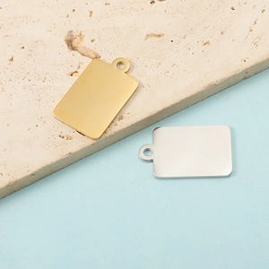 Detailed view of polished gold and silver rectangular DIY pendants on a textured stone