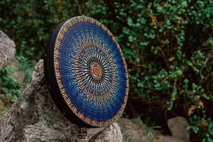 Macro detail of a mosaic drum with a blue mandala pattern on a natural rock setting