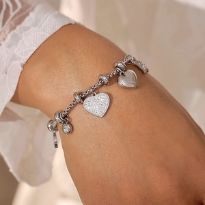 Silver-tone heart charm bracelet with sparkling crystals on a woman's wrist