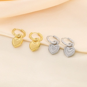 Gros plan de boucles d'oreilles pendantes cœur en or et argent sur tissu en soie