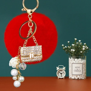 Close-up of red fur ball keychain with rhinestone handbag charm and pearl tassel