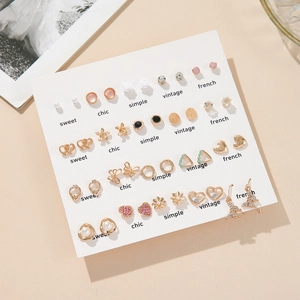 Detail view of 25 pairs gold plated heart and faux pearl stud earrings on display card