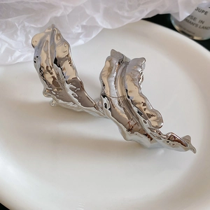 Macro shot of silver liquid metal leaf arm cuff with high-shine polished finish texture