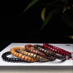 Bracelets minimalistes en bois de santal en cinq couleurs sur un livre blanc