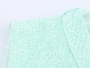 Close-up of mint green tweed fabric texture and shoulder stitching details
