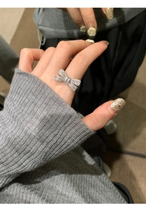 Close-up of a bow-knot silver ring set with sparkling zircons worn on a finger