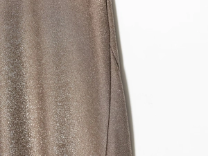 Dettaglio macro del tessuto metallico color champagne con trama a maglia fine