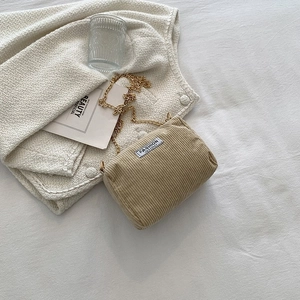 Detailed close-up of corduroy texture and gold chain strap on the khaki crossbody bag