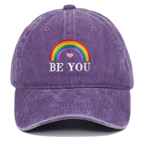 Detail of rainbow and BE YOU embroidery on washed purple cotton baseball cap surface