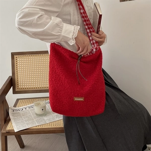 Detalle del bolso tote de felpa roja con textura de lana de cordero y correa de cuadros