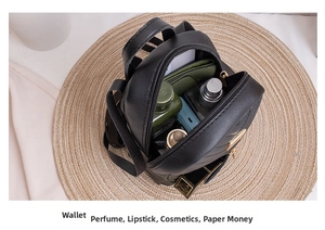 Internal view of mini black quilted backpack showing storage for cosmetics and wallet