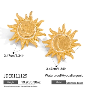 Macro detail of gold stainless steel sun and moon earrings with embedded crystals