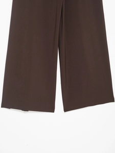 Dettaglio del tessuto marrone scuro e dell'orlo piatto di questi pantaloni larghi