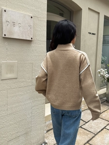 Close-up back view of camel knit sweater with white trim detailing and full zipper