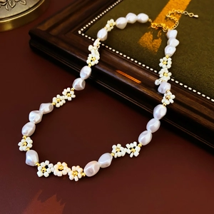 Detailed macro view of baroque pearl necklace with beaded gold flowers and metal clasp