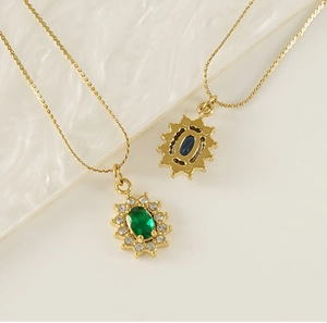 Detailed shot of gold necklaces with oval green and blue gems in sparkling crystal frames