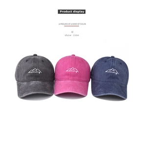 Detailed view of washed cotton baseball caps in navy, pink, and grey with mountain embroidery