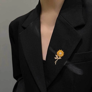 Detailed close-up of a sunflower brooch with yellow petals and crystals on a black suit