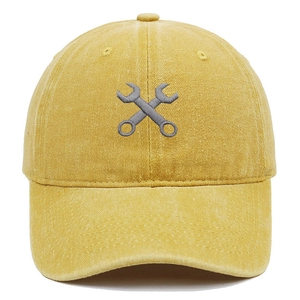 Détail de la broderie de clés croisées sur une casquette en coton lavé jaune