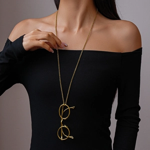 Long gold necklace with unique round glasses frame pendant worn by a female model