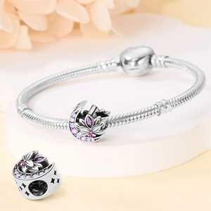 Detailed macro view of silver snake chain bracelet featuring moon and lotus charms