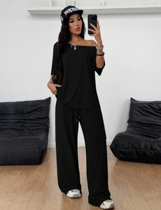 Detalle de conjunto negro de dos piezas con top de hombros caídos y pantalones anchos de punto
