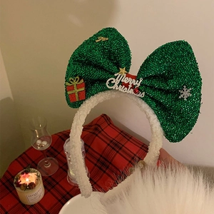 Detail of Christmas headband with green glitter bow, gift box and Merry Christmas plaque