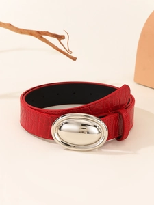 Close-up of red crocodile pattern leather belt with oval silver polished metal buckle