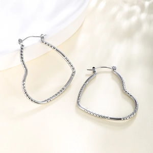 Close-up of silver heart hoop earrings featuring intricate textured chain pattern detailing