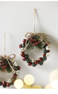 Detail of Christmas bell wreath with pine needles and berries hanging on a white wall